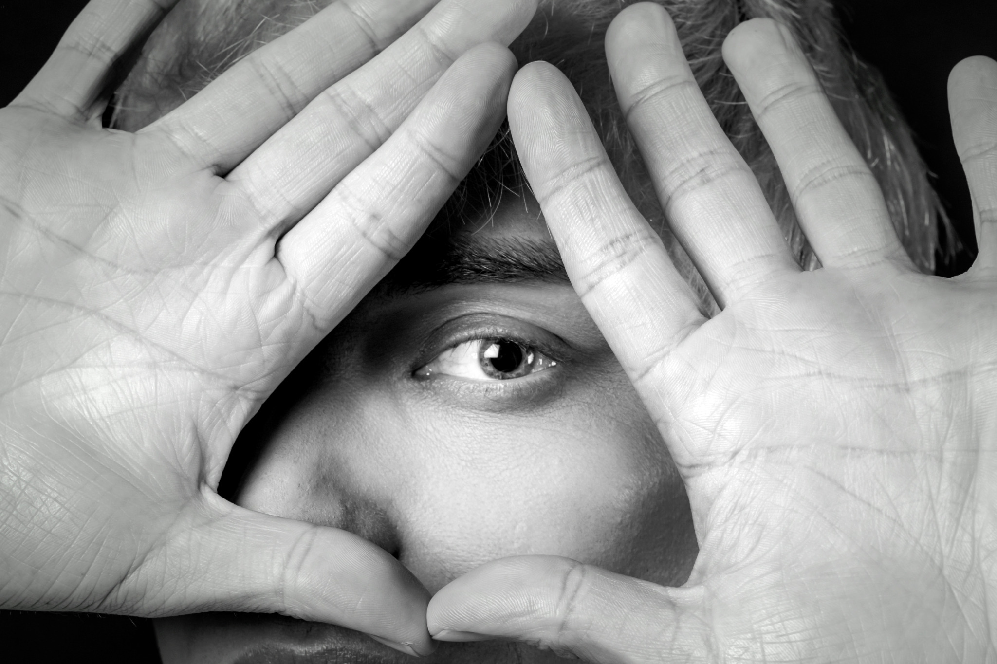 Black-and-white close portrait of Charlie Void framing one eye with both hands