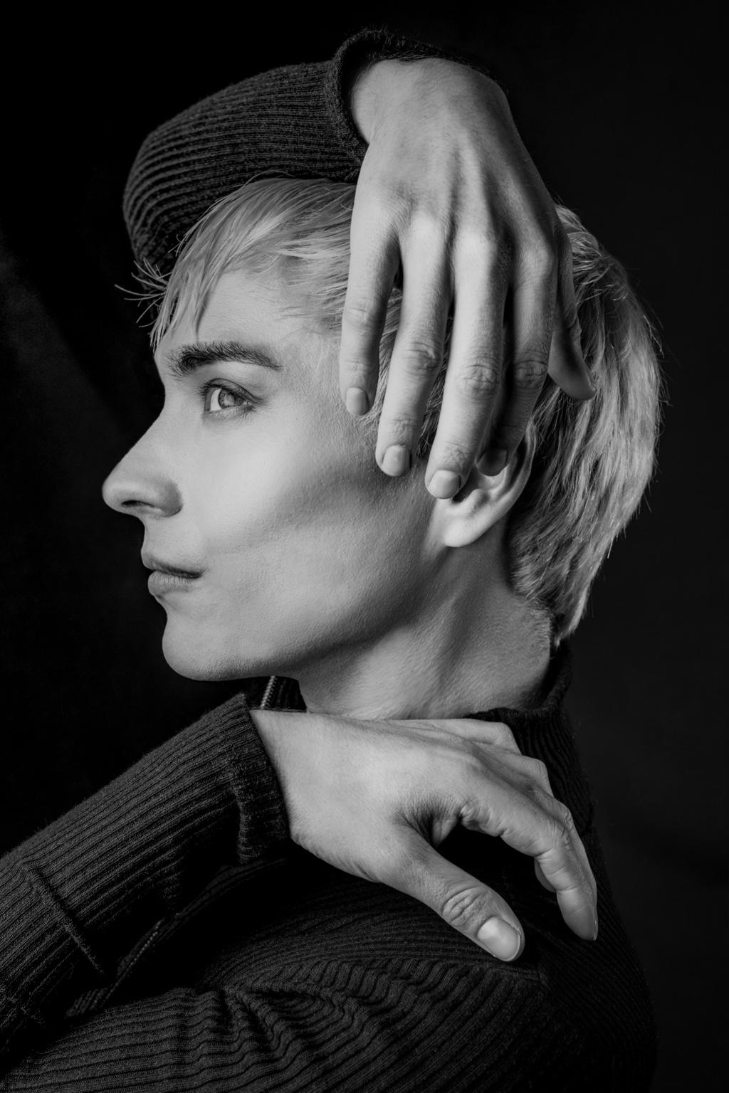 Black-and-white profile portrait of Charlie Void framed by sculptural hand placement