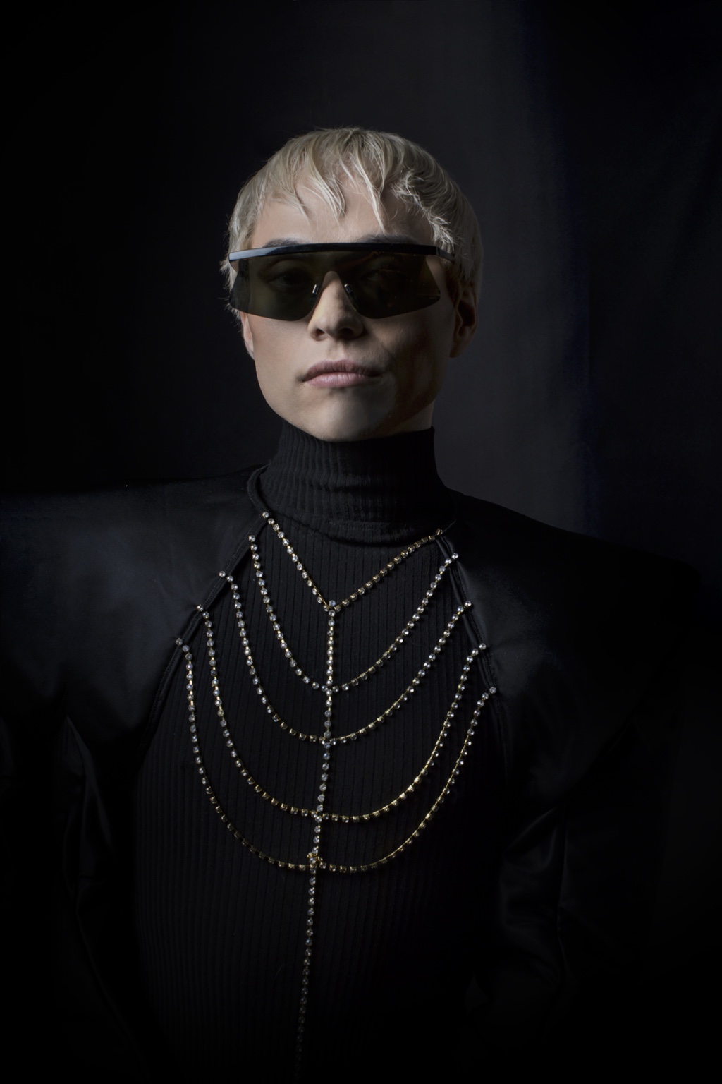 Charlie Void in black architectural tailoring, shield sunglasses and crystal body jewellery